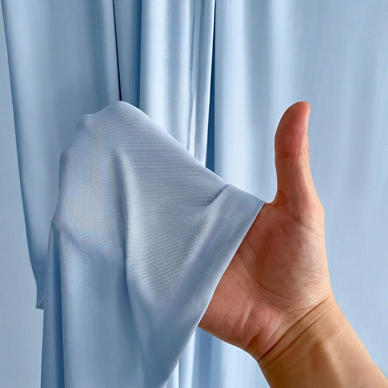 A hand holding a fold of the sky blue fabric, showing its thin, soft texture.